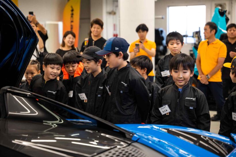 Children try changing a McLaren tire at McLaren Kids Engineering